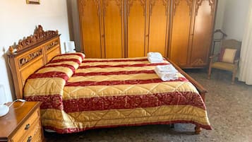 Ein Schlafzimmer mit einem großen Bett, einem Holzschrank, einem Schminktisch und einem Stuhl.