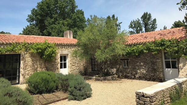 A stone building with a red-tiled roof, a small window, and a door.