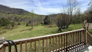 A wooden deck with a view of a grassy field and trees. - Spacious, Sunlit, 3 Bedroom, 2 Bath Home in East Asheville (Asheville)