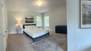 Een slaapkamer met een bed, nachtkastje, lamp en een poster van Claude Monet.
