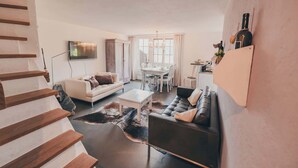 Una sala de estar moderna con una escalera, un comedor y una cocina.