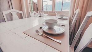 Una mesa de comedor dispuesta con un tazón blanco, un plato y un tenedor, rodeada de sillas.