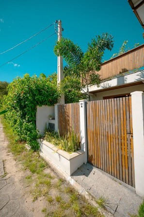 A modern house with a wooden fence, a number 51A sign, and a clear blue sky. - Studio Para 2 c Ar-condicionado na Barra da Lagoa (Florianópolis)