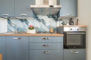 Eine moderne Küche mit grauen Schränken, einer Marmor-Spritzschutzleiste, Edelstahlgeräten und einer Holz Arbeitsplatte.