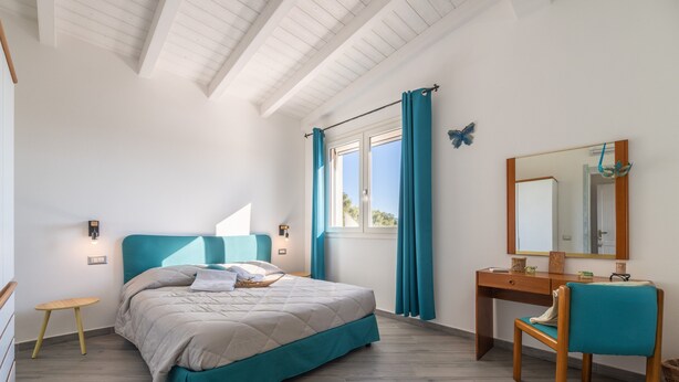 Une chambre à coucher comprenant un lit, un bureau, une chaise, une fenêtre avec des rideaux, un miroir et un plafond en bois.