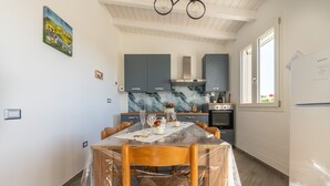Een moderne keuken met grijze kastjes, een marmeren spatwand en een eethoek met een tafel voor vier personen.