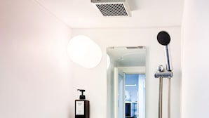 A modern bathroom with a shower, a mirror, and two shelves with toiletries. - Triphome Koenji Minami 4 mins Higashi Koenji station (Suginami City)