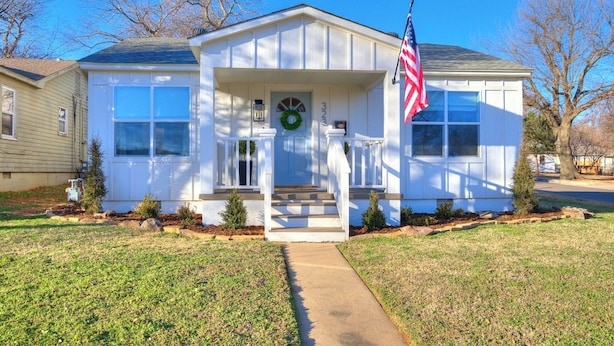 Ein eingeschossiges Haus mit Veranda, Eingangstür und einer amerikanischen Flagge.