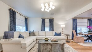 Una sala de estar con un sofá seccional, una mesa de centro y una zona de comedor con una mesa y sillas.