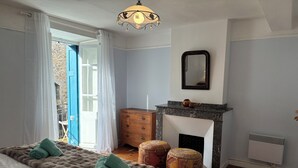 A bedroom with a bed, a dresser, a fireplace, and a mirror. - Spacious Village House with Garden in Ginoles (Ginoles)