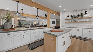 Een moderne keuken met witte kasten, houten balken, hanglampen en een centraal eiland.