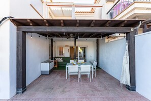 An outdoor patio with a wooden pergola, a dining table with chairs, and a white sofa. - Villa in Granada With Private Terrace (Almunecar)