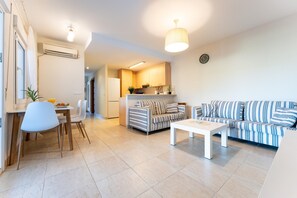 A modern living room with a sofa, a dining table with chairs, a kitchen area, and a ceiling light fixture. - Villa in Granada With Private Terrace (Almunecar)