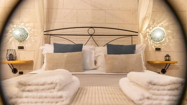 A bed with a metal frame, two pillows, a blanket, and two bedside tables with lamps. - L'Accademia dei Sogni (Sassari)