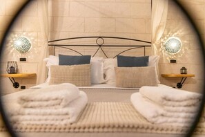 Ein Bett mit Metallgestell, zwei Kissen, einer Decke und zwei Nachttische mit Lampen.