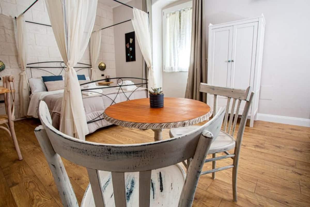 Une chambre à coucher comprenant un lit, une table de chevet, une chaise, une table ronde et un lit à baldaquin.
