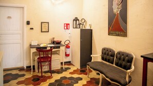 A hotel room with a dining area, a fire extinguisher, a clock, and a painting on the wall. - L'Accademia dei Sogni (Sassari)