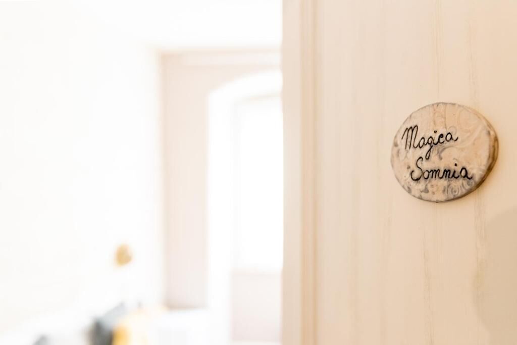 A wooden door with a circular sign that reads 'Magica Somnia.'