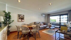 Een woonkamer met een eethoek, een bank en een groot raam.