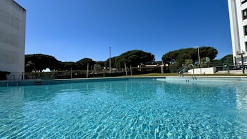 A clear swimming pool with a view of surrounding buildings and trees.
