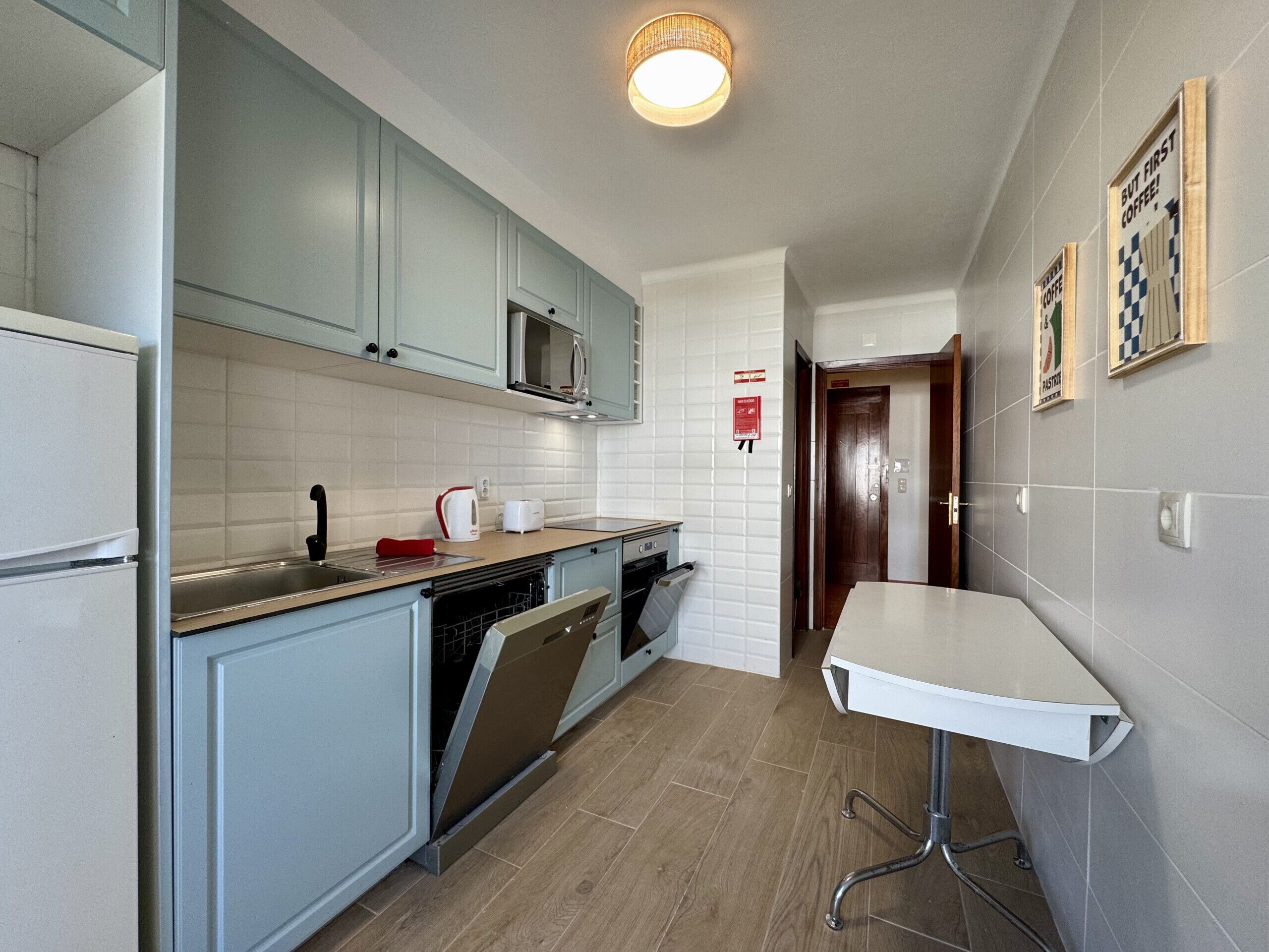 A compact kitchen with a dishwasher, microwave, and a small dining table.