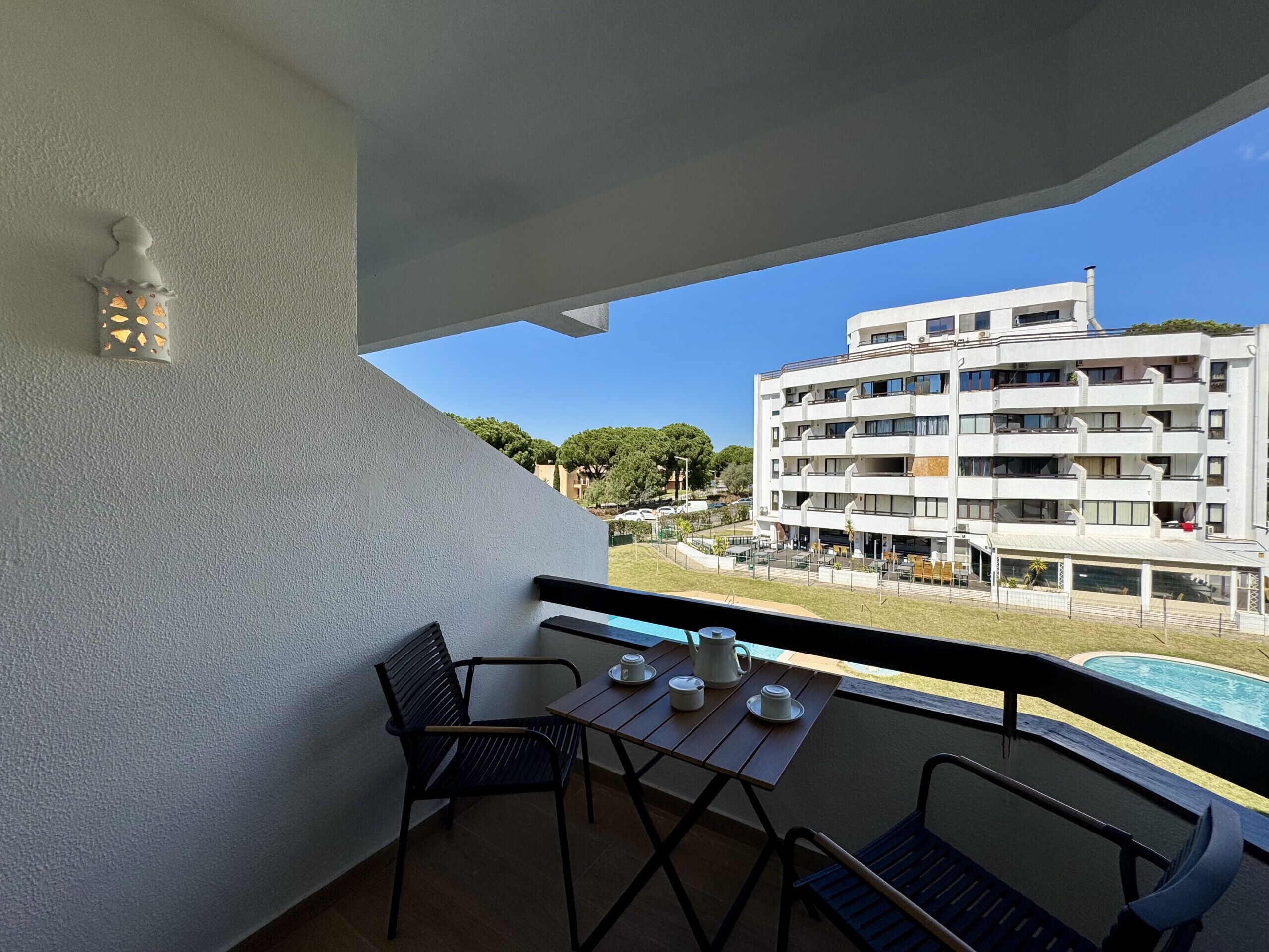Un balcón con una mesa, sillas y vistas a un edificio moderno.
