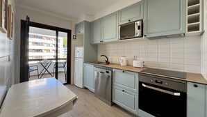 A modern kitchen with a dishwasher, oven, microwave, and a dining area with a table and chairs. - Vilamoura Charming 2 With Pool by Homing (Loulé)