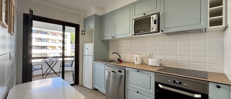 Una cucina moderna dotata di lavastoviglie, forno, microonde e zona pranzo con tavolo e sedie.