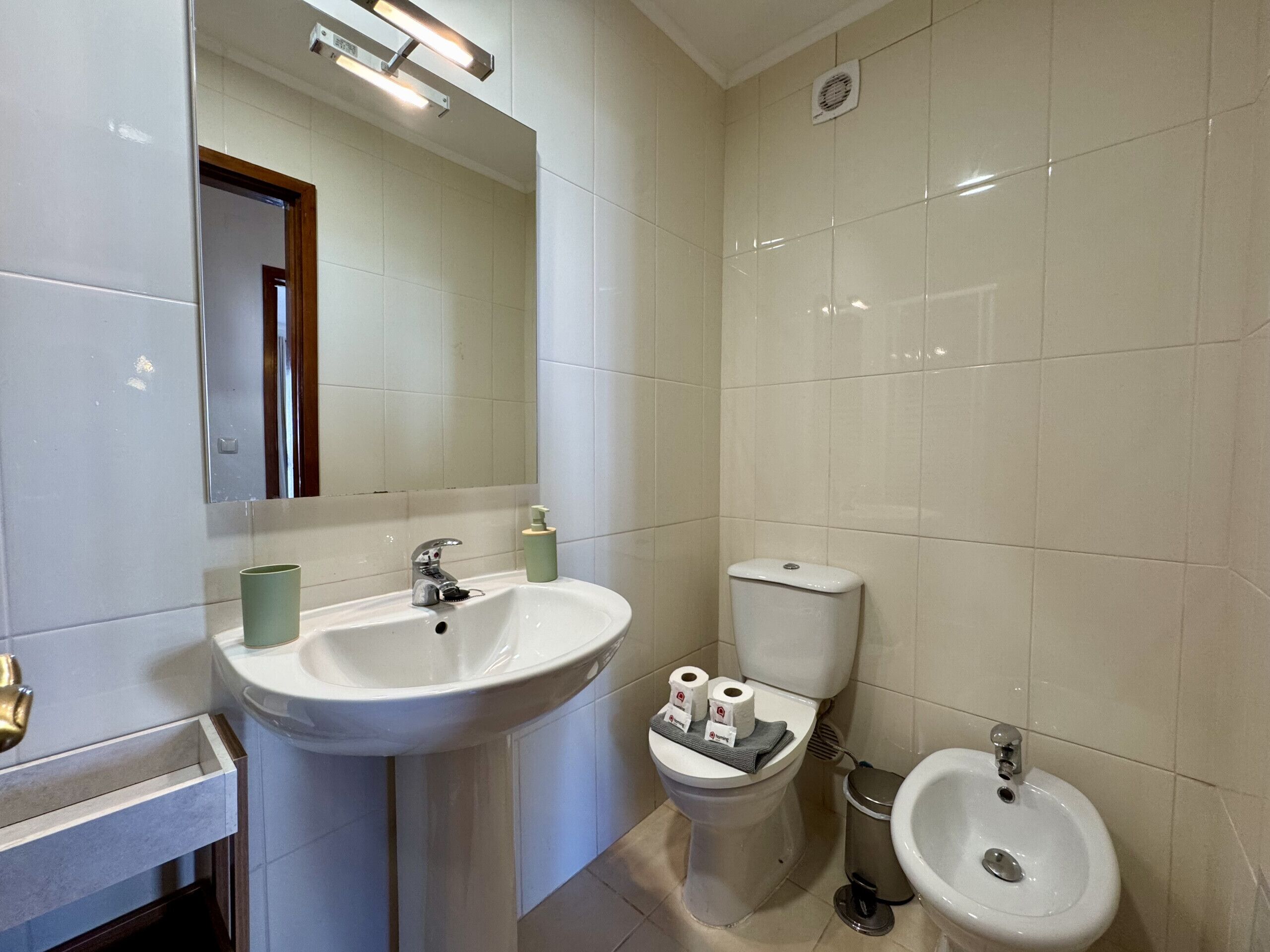 Un baño con lavamanos, inodoro, bidé y espejo.