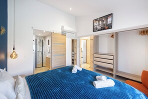 A modern hotel room with a large bed, a walk-in closet, and a bathroom with a glass shower enclosure. - Magnificent villa with sea view, heated swimming pool (optional), pétanque and table tennis. (Roquebrune-sur-Argens)
