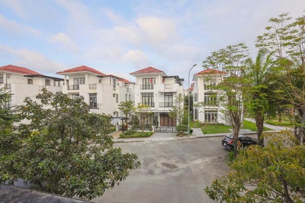 A residential building with multiple balconies, a central entrance, and a parking area. - NGOC THIEN MINH HOMESTAY (Hue)