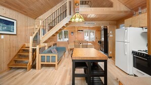 Un intérieur en bois comprenant un escalier, un coin repas et une cuisine.