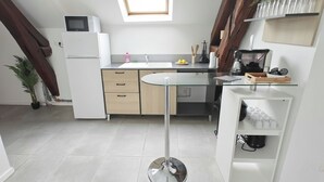 A modern kitchen with a central island, a microwave, a refrigerator, and a coffee machine.