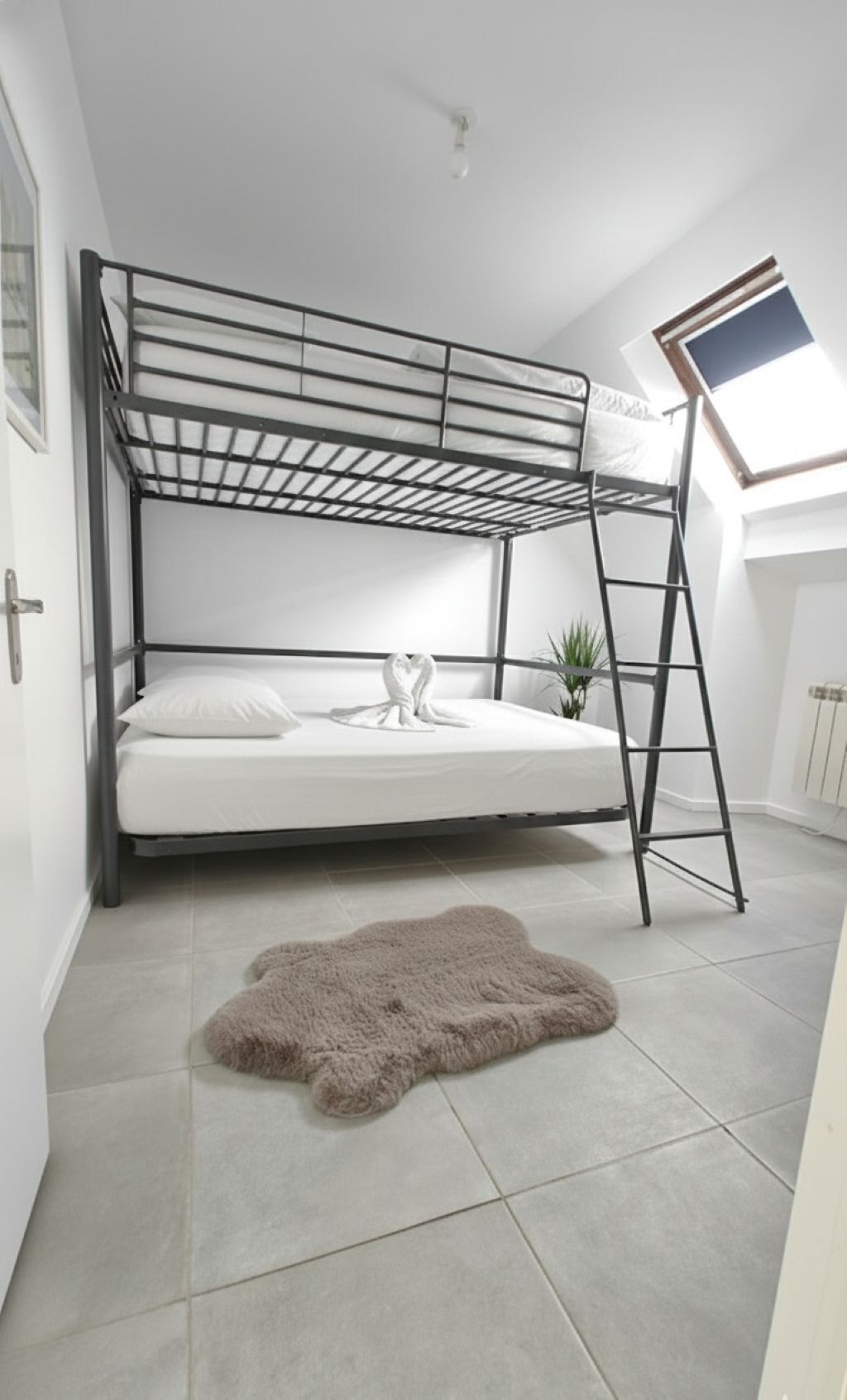 Een stapelbed met een ladder, een wit matras, een zacht tapijt en een dakraam.