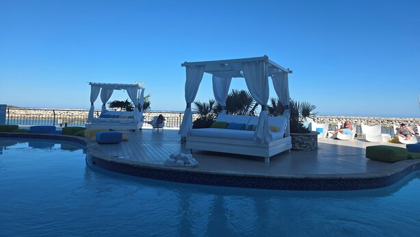A poolside area with two canopy beds and a view of the beach. - Spacious 5-bedroom villa/AC at beach resort
15 restaurants/bars. 
All Inclusive! (Cofresi)