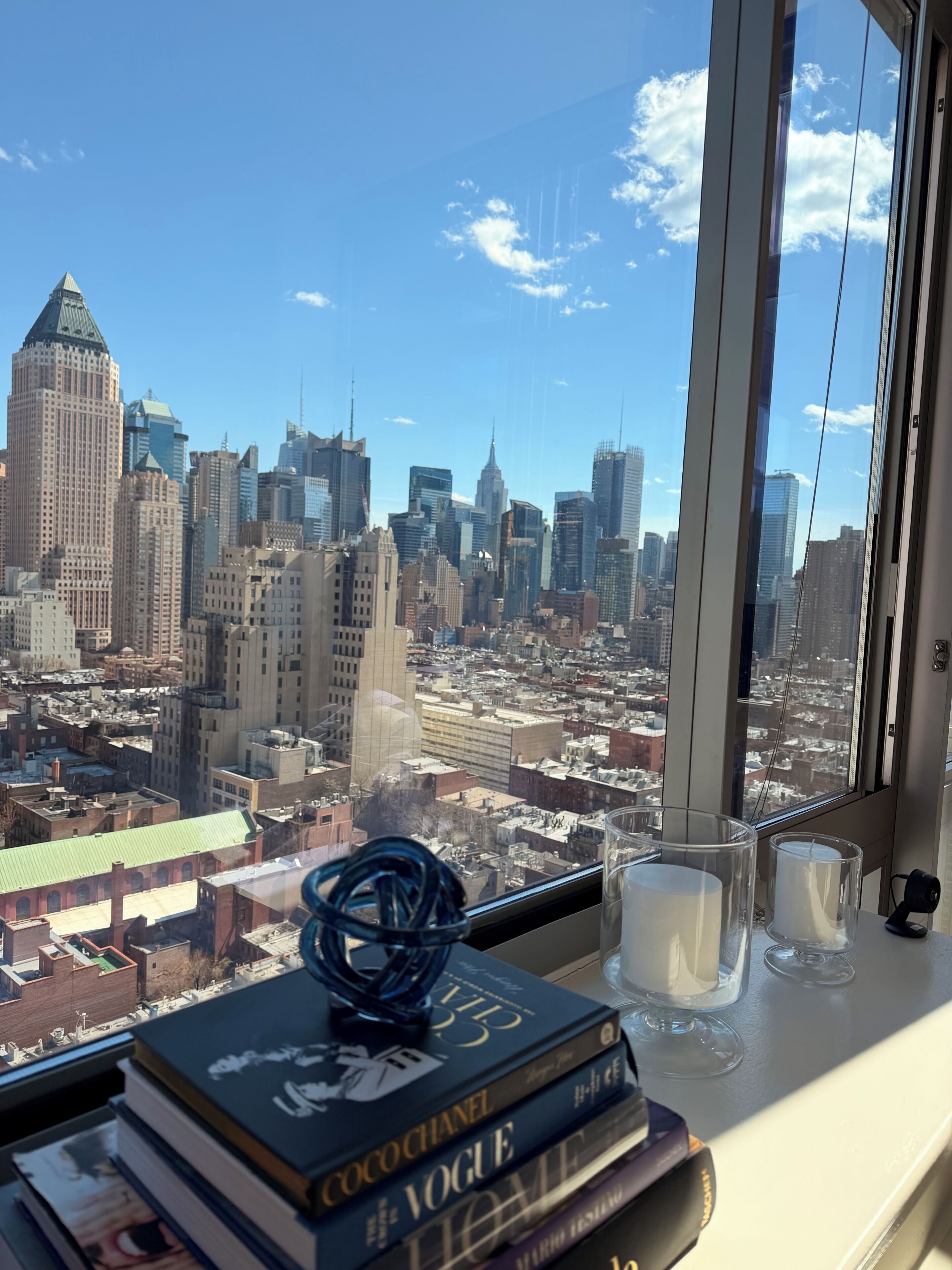 A cityscape view from a high-rise window, featuring a variety of building styles and a clear sky.