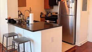 A modern kitchen with wooden cabinets, stainless steel appliances, and a central island with bar stools. - Luxury NYC Penthouse with Amazing Views (New York)