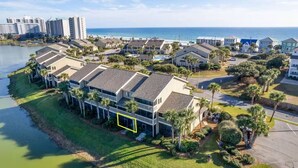 A coastal residential area with beachfront properties, including a row of townhouses with balconies, a marina, and a view of the ocean. - Coastal Escape with Lake Views & Beach Days Just Minutes Away (Miramar Beach)