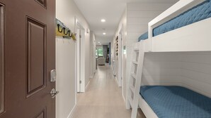 A narrow hallway with bunk beds, a door with a key lock, and a hallway leading to a room with a view. - Coastal Escape with Lake Views & Beach Days Just Minutes Away (Miramar Beach)