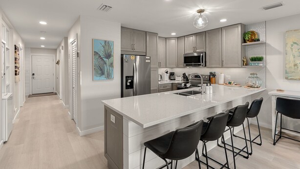 A modern kitchen with grey cabinets, a large island with bar stools, stainless steel appliances, and a pendant light. - Coastal Escape with Lake Views & Beach Days Just Minutes Away (Miramar Beach)