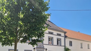 Un bâtiment à deux étages avec une porte rouge, de nombreuses fenêtres et un toit recouvert de tuiles.
