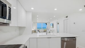 Una cocina moderna con armarios blancos, microondas integrado y lavavajillas.