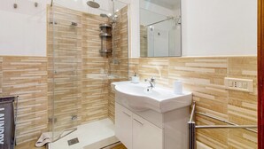 Une salle de bain moderne avec une douche à parois de verre, un lavabo blanc et un miroir au-dessus.