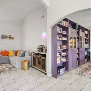 A living room with a grey sofa, colorful cushions, a purple bookshelf, and a patterned rug. - Cozy 3BR / 2BA Getaway / Legoland / Winterhaven / Lakeland (Lakeland)