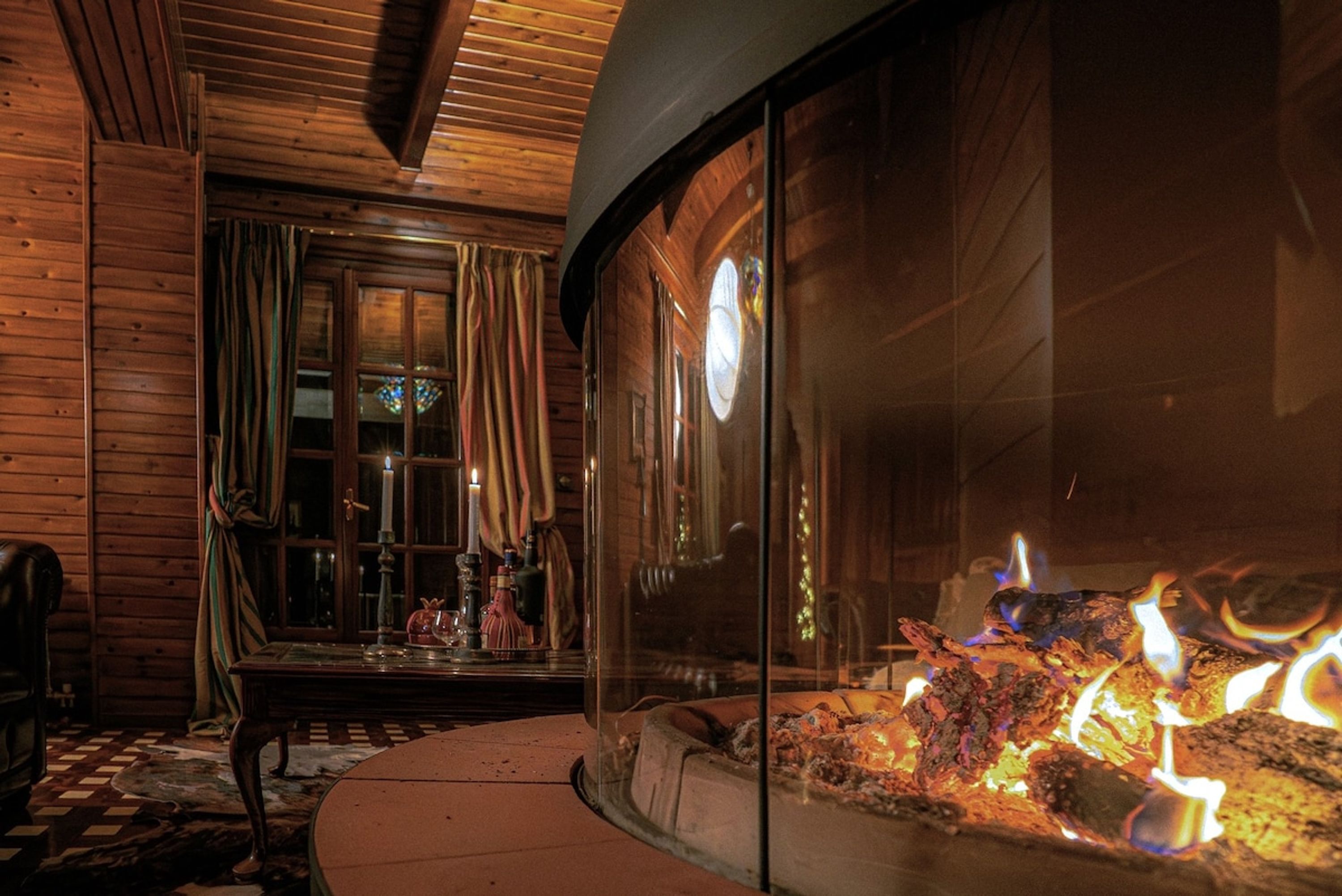 A cozy room with wooden walls, a glass fireplace, and a checkered floor.