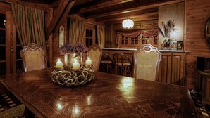 Uma mesa de jantar de madeira com velas, cadeiras e um vaso de flores.