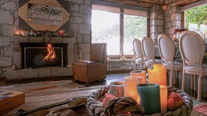 Um quarto com paredes de pedra, lareira, mesa de jantar com cadeiras e velas.