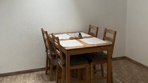 A dining area with a wooden table and four chairs, a small table lamp, and a book on the table. - BELLESTAY/Suite for 4 (Brașov)