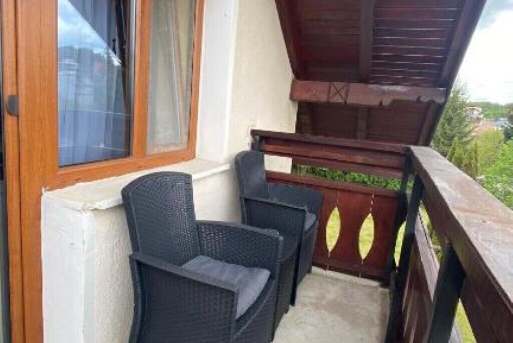 A balcony with wicker furniture and a wooden railing.