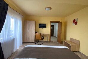 A hotel room with a bed, a desk, a chair, a television, and a wardrobe. - BELLESTAY/Suite for 4 (Brașov)